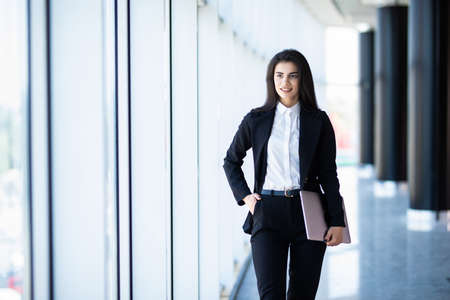 Young pretty woman with laptop in office hall with panoramic windowsの写真素材