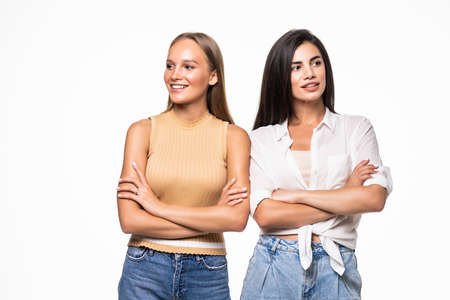 Image of smiling beautiful two women posing with hands crossed on camera isolated over white backgroundの写真素材