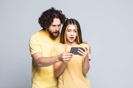 Happy friends laughing and watching a smart phone isolated on a white background