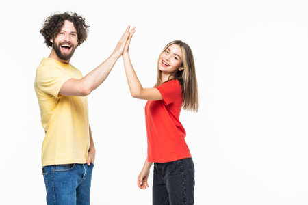 Portrait of a beautiful young couple standing and giving high five isolated on the gray backgroundの写真素材