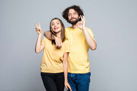 Young couple make peace and okay gesture on gray backgroundの写真素材