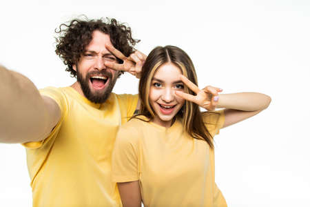 Attractive couple taking a selfie together on white background