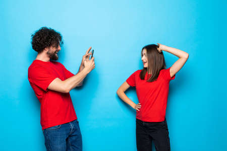 Beautiful couple making a photo with phone on blue backgroundの写真素材