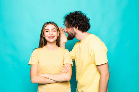 Couple is listening gossip in the ear each other on the turqouise background.の写真素材