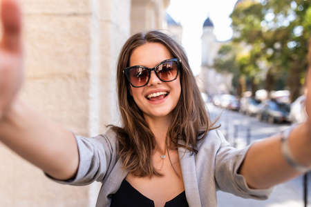 Pretty young woman takes a selfie in the city streetsの写真素材