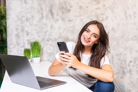 Young woman working from home office. A freelancer uses a laptop, phone, internet and notepad.
