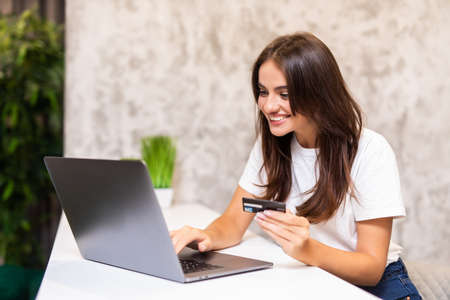 Young woman holding credit card and using laptop computer.の写真素材