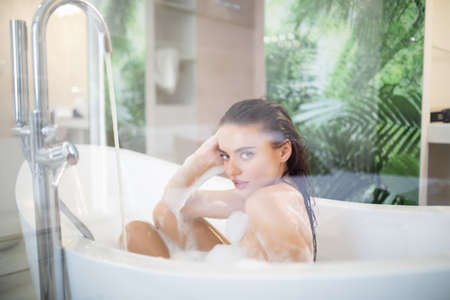 attractive woman taking bath with foam at homeの写真素材