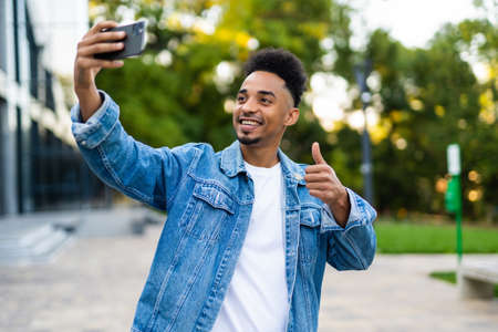 Handsome smiling African American man showing thumb up to camera. Self portrait concept