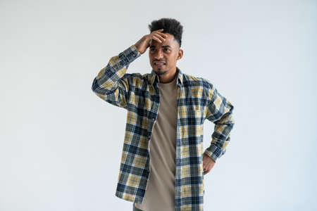 Portrait of shocked young African American man holding hands on head.