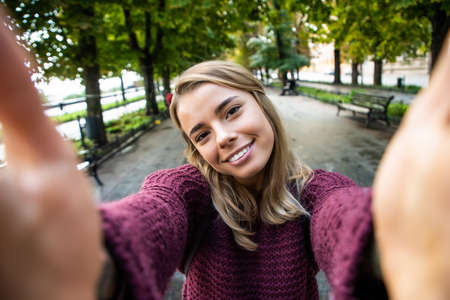 Young and beautiful. Elated pretty woman making selfie while having a walk around the city