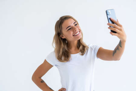 Young beautiful woman using smartphone selfie time, holding coffee cup and mobile phone on white background .. Lifestyle concept.の写真素材