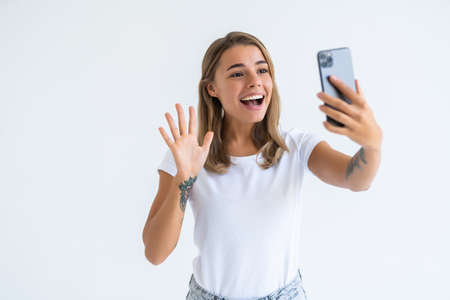 Happy young woman blogger influencer holding modern smart phone wave hand hello. Smiling vlogger...