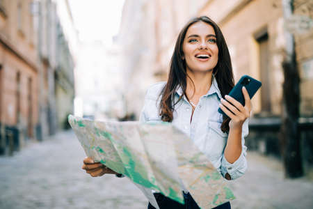 Young traveler woman planning trip with map and smartphone.の写真素材