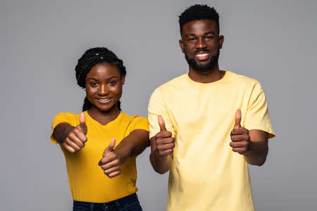 African couple showing thumbs up gesture isolated on gray studio background,の写真素材