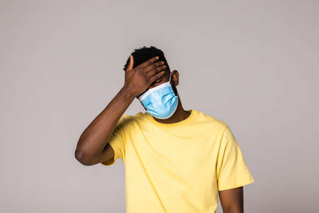 health, pandemic and safety concept - african american young man wearing face protective medical mask for protection from virus disease over gray backgroundの写真素材