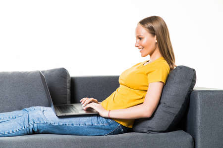 Woman lying on sofa at home working on laptop computer. on white background.の写真素材