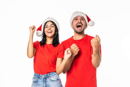 Young pretty couple in love wearing christmas hat over isolated background celebrating crazy and amazed for success with arms raised and open eyes screaming excited. Winner conceptの写真素材