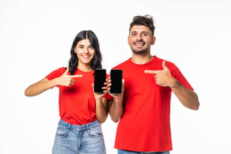 Young couple showing smartphone screen over isolated background pointingの写真素材