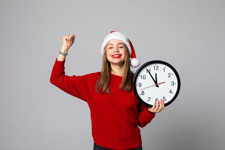 Young woman in Santa hat with clock on light background. Christmas countdown conceptの写真素材