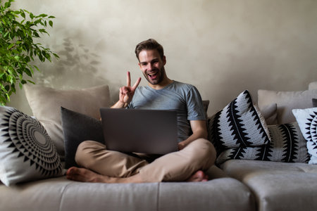 Happy young man having a video call with a laptopの写真素材