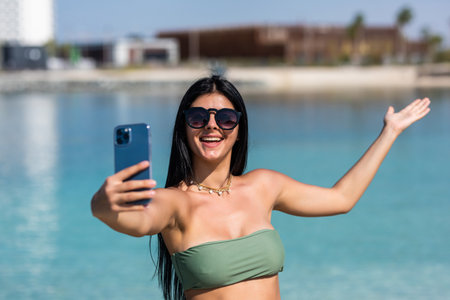Beautiful young woman doing selfie on the beachの写真素材