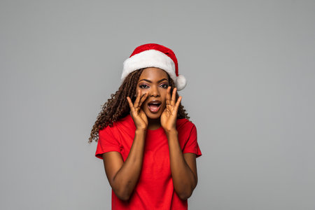 Beautiful american woman in santa hat on gray backgroundの写真素材