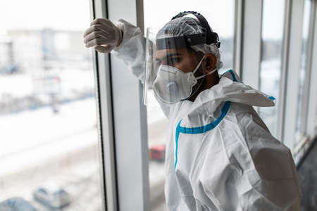 Man in Hazmat protective suits look glass at home or office during outbreakの写真素材
