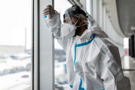 Man in Hazmat protective suits look glass at home or office during outbreak