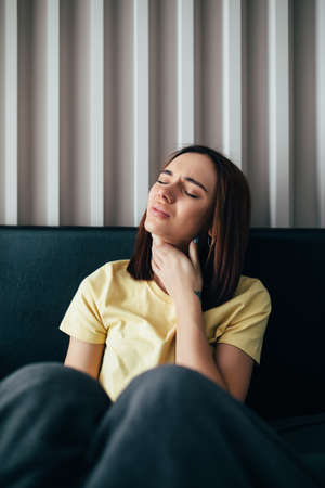Young woman with sore throat sitting on her bed