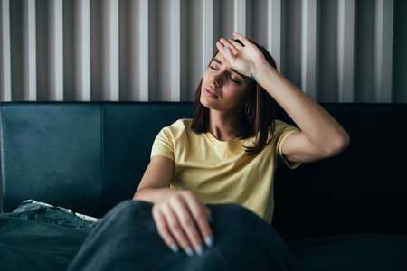 Young beautiful Caucasian woman on bed having headache insomnia migraine stress
