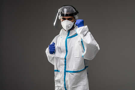 Man doctor in overall protection hazmat suit fighting pandemic on gray backgroundの写真素材