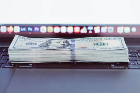 Laptop and US dollar money, Computer notebook and dollar banknotes on a wooden background, Technology with US dollar bank note,の写真素材