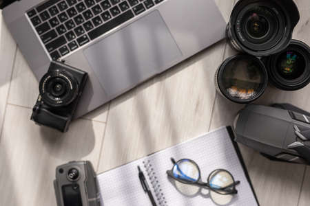 Layout of gadgets top view on a wooden background. Hi tech Travel gadgets, mobile phone, camera, lens, notebook and glasses, laptop.の写真素材