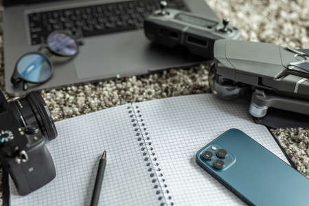 quadrocopter, accessories for drones, phone and laptop, glasses and camera near the sheet for making a listの写真素材