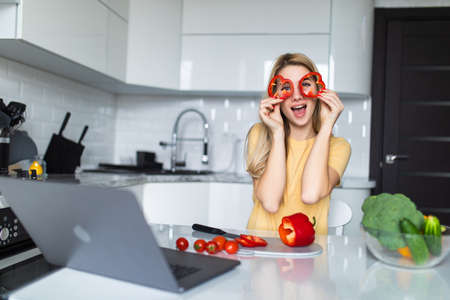 Young housewife playing with food cut slices of sweet paper while cooking in the kitchen. Healthy food at home.の写真素材