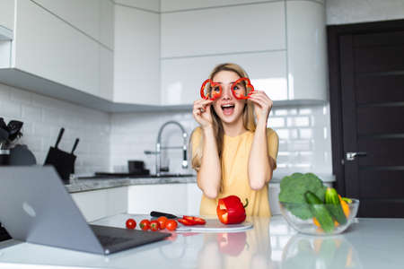 Young housewife playing with food cut slices of sweet paper while cooking in the kitchen. Healthy food at home.の写真素材