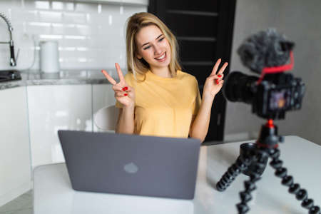 Young girl recording a video tutorial smiling and showing victory signの写真素材