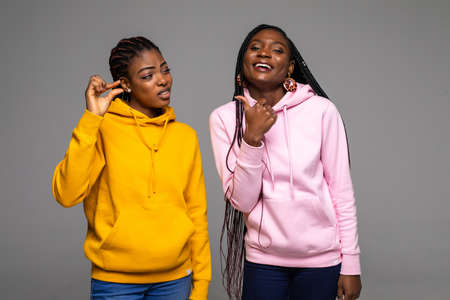 Two african friends standing together over gray background smiling and confident gesturing with hand doing small size sign with fingersの写真素材