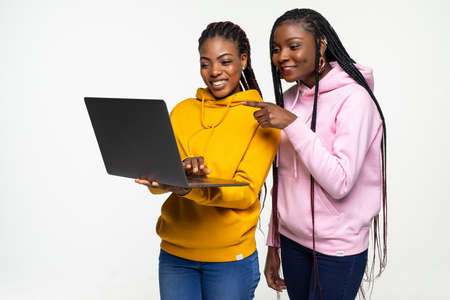 Two young women s friends working on laptop pc computer posing isolated on white background. People lifestyle concept.の写真素材