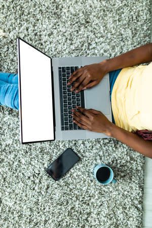 Top view african woman use laptop sitting on carpet floor at home.の写真素材