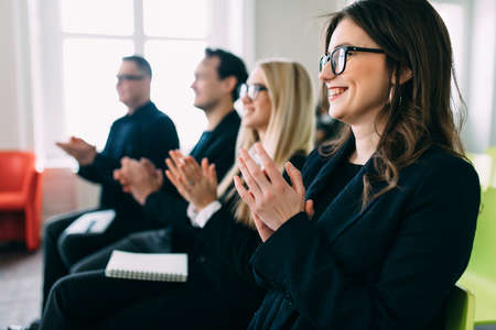 Happy smiling business team clapping hands during a meeting in office