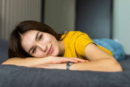 Pretty young woman lying down on her bed at home