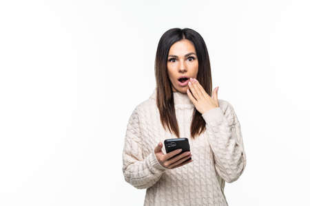 Young beautiful woman use smartphone excited surprised news information isolated over white backgroundの写真素材