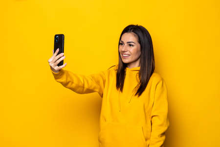 Smiling brown-haired girl posing with tongue out. Close-up portrait of adorable pretty lady in good mood making selfie on bright background.の写真素材