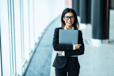 Young business woman with laptop in office hall with panoramic windowsの写真素材
