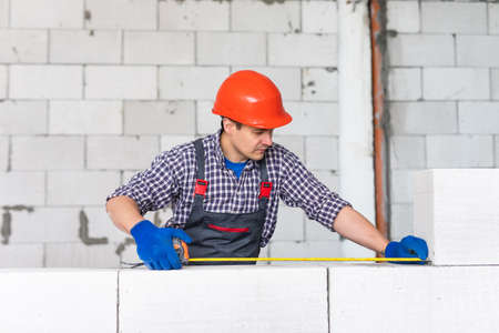 bricklayer man builder working with autoclaved aerated concrete blocks. Walling