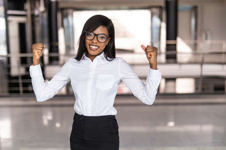 Portrait of young black Business woman hands up happy in the success officeの写真素材