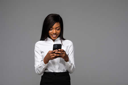 Portrait African American businesswoman using phone isolated on gray backgroundの写真素材