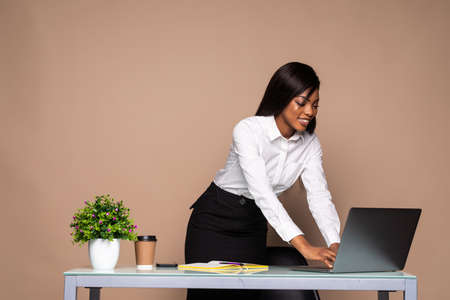 Young african businesswoman standing over laptop at office deskの写真素材